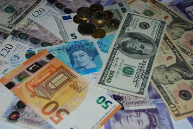 Farklı ülkelerden gelen banknotlar ve paraların yer aldığı çeşitli küresel para birimleri, uluslararası finans ve ekonomik değişimi sembolize ediyor.