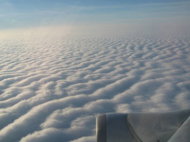 Suyun üzerindeki dalgaları andıran geniş bulut oluşumlarının yukarıdan görünüşü uçarken görüntülenir. Yumuşak, dalgalı dokusu gökyüzünde sakin ve sakin bir atmosfer yaratıyor..