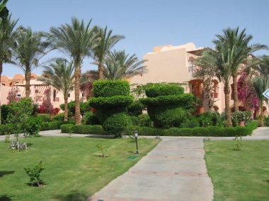 Manikürlü bahçeler, canlı bitkiler ve palmiyeler güzel manzaralar sergiliyor. Huzurlu bir yürüyüş yolu yeşillik boyunca esiyor, tatil köyünde sakin bir atmosfer yaratıyor..