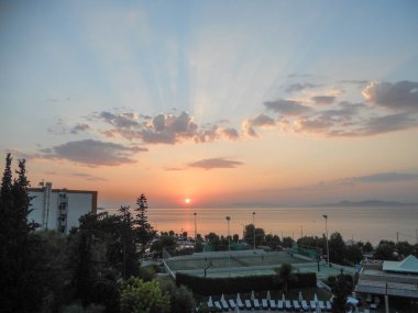 Huzurlu bir deniz manzarası ufukta batan güneşi yakalar ve gökyüzünde canlı renkler bırakır. Sakin sular resim sahnesini yansıtıyor. Rahatlama ve sükuneti davet ediyor..