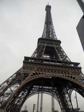 Ziyaretçiler Eiffel Kulelerine hayranlık duyarken bulutlar gökyüzünü kaplıyor. Aşağıdan gelen karmaşık demirler. Bu sembolik simge, mimari güzelliğini ve tarihsel önemini gözler önüne sererek dimdik ayakta duruyor..