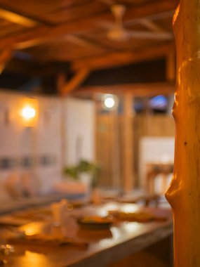 A blurred view of a cozy restaurant interior. The warm lighting and wooden beams create a welcoming atmosphere. Blurred background restaurant concept. Selective focus restaurant interiors. clipart