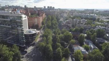 Arkasında büyük bir bina olan bir şehir manzarası. Şehir ağaçlar ve binalarla dolu.