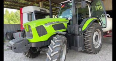 Yeşil ve sarı traktör bir tarlaya park edilmiş..