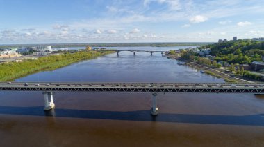 Köprü, arka planda bir şehir bulunan bir nehri kapsar. Köprü nehrin iki tarafını birbirine bağlayan büyük bir yapıdır.