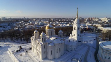 Merkezinde büyük beyaz bir kilise olan karlı bir şehir. Kilise büyük bir avluyla çevrili ve tepesinde altın bir kubbe var. Şehir, etrafta dolaşan insanlarla dolup taşıyor.