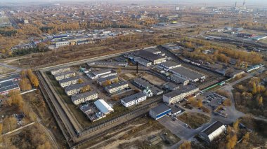 Ortasında büyük bir bina ve etrafı çitlerle çevrili bir şehir manzarası. Çit metalden yapılmıştır ve çok uzundur.