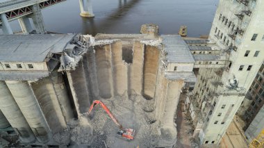 Büyük bina bir vinçle yıkılıyor. Vinç ön planda ve bina da arka planda.