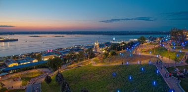 Geceleri arka planda büyük bir su kütlesi olan bir şehir. Şehir mavi ışıklarla aydınlanıyor, sakin ve huzurlu bir atmosfer yaratıyor. Nizhny Novgorod