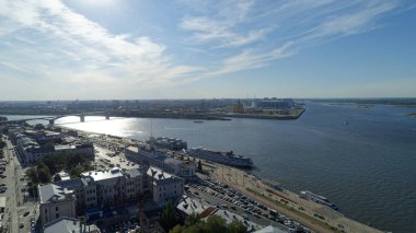 İçinden nehir akan bir şehir. Su sakin ve gökyüzü berrak. Suda bir sürü tekne ve sokaklarda arabalar var. Nizhny Novgorod