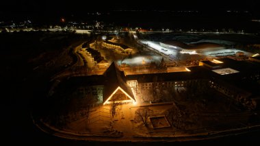 Merkezinde büyük bir bina olan bir kasabanın gece görüşü. Binanın bir üçgen çatısı var ve ışıklandırılmış. Kasaba karla kaplı. Suzdal.