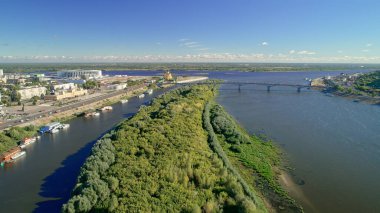 İçinden nehir akan bir şehir. Nehir ağaçlar ve evlerle çevrilidir. Nehirde kayıklar ve uzakta bir köprü var. Nizhny Novgorod