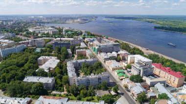 Arka planda nehir olan şehir manzarası. Binalar yüksek ve bir sürü ağaç var. Nizhny Novgorod