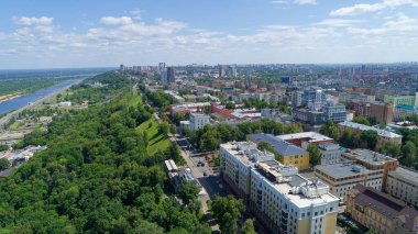 Şehir manzarası ve içinden bir nehir geçiyor. Şehir yüksek binalar ve yeşil ağaçlarla dolu. Nizhny Novgorod