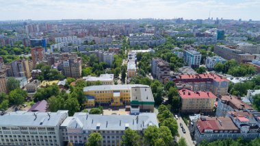 Şehir manzarası bir sürü bina ve ağaçla dolu. Binalar yüksek ve ağaçlar yeşil. Gökyüzü mavi ve bulutlar var. Nizhny Novgorod