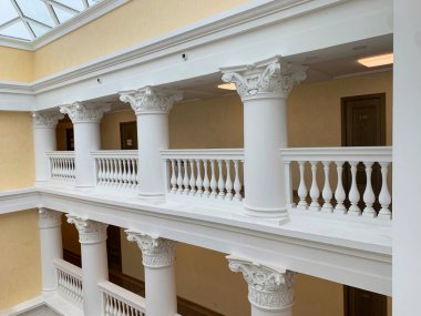 Geniş, beyaz sütunları ve cam tavanı olan açık bir alan. Sütunlar beyaz ve dekoratif bir tasarıma sahip. Mekana büyük ve zarif bir his veriyor. Cam tavan açıklık hissi katıyor.