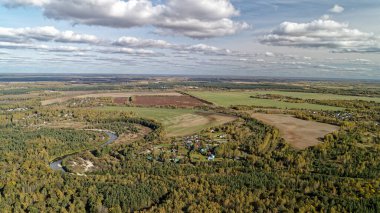 Kırsal kesimde içinden nehir akıyor. Gökyüzü bulutlu ve arazi çoğunlukla yeşil. Nizhny Novgorod bölgesinde sonbahar ormanı. Rusya.