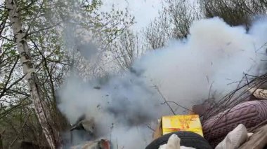 Bir çöp yığını bir ormanda yerde. Çöpte bir lastik, bir kutu ve bir battaniye var. Olay yeri dağınık ve dağınık. Çöpler her yere saçılmış. Çok güçlü bir havai fişeğin patlaması