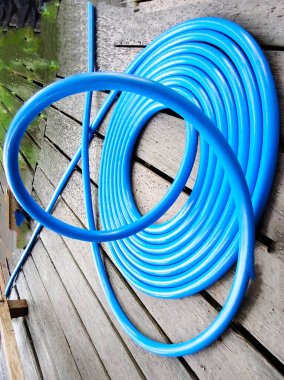 Plastik su borusu ve tahta arka planda plastik hortum.