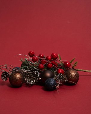 Ağaç dallar ve yeni yıl oyuncakları üzerinde koni ve kırmızı böğürtlen