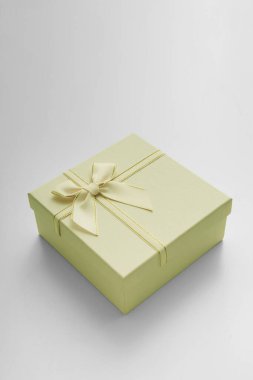 Kurdeleli hediye kutusu ve beyaz arka planda fiyonk. Hediye kutusu desenli. Açık gri arkaplanda desenli kutu uzanır