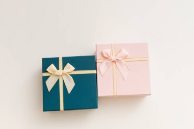 Kurdeleli hediye kutusu ve beyaz arka planda fiyonk. Hediye kutusu desenli. Açık gri arkaplanda desenli kutu uzanır