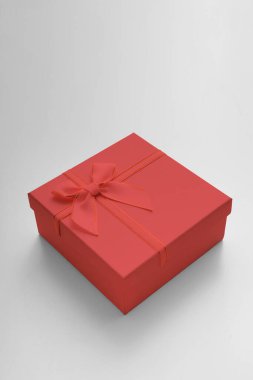 Kurdeleli hediye kutusu ve beyaz arka planda fiyonk. Hediye kutusu desenli. Açık gri arkaplanda desenli kutu uzanır