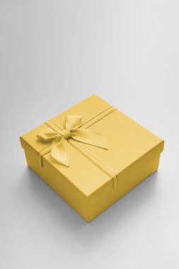 Kurdeleli hediye kutusu ve beyaz arka planda fiyonk. Hediye kutusu desenli. Açık gri arkaplanda desenli kutu uzanır