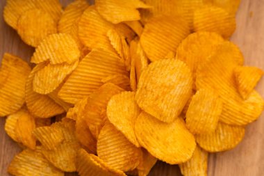 Bowl of crispy potato chips or crisps with salt isolated on white background, top view