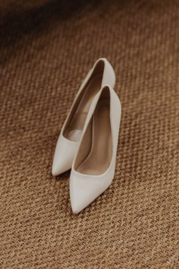 Gelin için zarif beyaz topuklar. Yakın çekim fotoğraf makrosu. Sarı halılı kadının ayakkabısında beyaz topuklar.