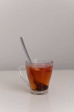 Çilekli çay, cam bardakta meyve dilimleri ve beyaz masada kaşıkla fotoğraf makro görüntüsünü kapatın.