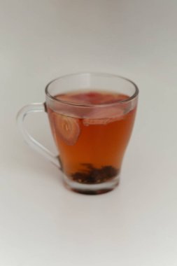 Berrak Bardakta çilek çayını tazeliyorum. Bardakta meyve dilimleri ve cam bardakta çilek çayıyla. Temiz Glasson beyaz arka plan makrosu içinde taze çilekler.