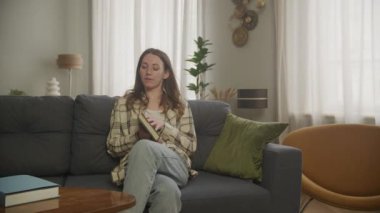 Kanepede oturan ve kitap okuyan kadın.