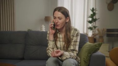 Genç, güzel, gülümseyen, beyaz bir kadın. Telefonla konuşuyor. Dairenin arkasından arıyor.