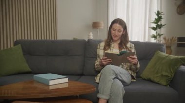 Düz bir kitap okuyan, gülümseyen, Kafkasyalı Kadın 'ın etrafında dönen bir kadın.