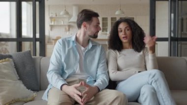 Evdeki koltukta oturan adamla konuşan neşeli kadın.