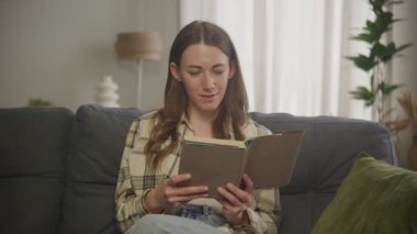 Beyaz Kadın Oturma Odasında Kanepe Üzerine Kitap Okuyor 