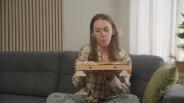 Dairedeki koltukta oturan kadın pizza yiyor.
