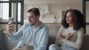 Mutlu Gülümseyen Çoklu Irkçı Çift Arkadaşlarıyla Oturup Video Konuşuyor, Karı-Koca Cep Telefonu Kullanıyor, yüksek kalite 4K görüntü