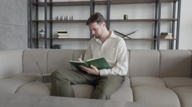 Ciddi Öz Güvenilir İşadamı Koltuğa Oturur ve Notepad 'a Bilgi Yazar, İngilizce Ödevi Yapan Adam, Yüksek Kaliteli 4k Görüntü