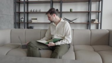 Odaklanmış İşadamı, Kanepede otururken Eğitimsel Video izlerken Önemli Noktaları Yazıyor, 4K 'lık yüksek kaliteli görüntü