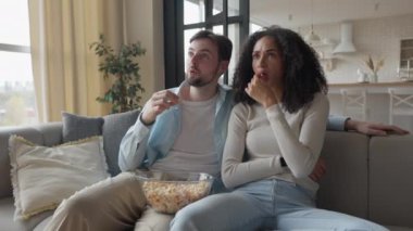 Irklar Arası Genç Çiftler Oturma Odasında Koltukta Birlikte Oturan Korkunç Film 'i izliyorlar, yüksek kalite 4K görüntü.