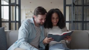 Erkek ve Kadın Çift Evde Koltukta Oturarak Kitap Okuyor, yüksek kalite 4K görüntü