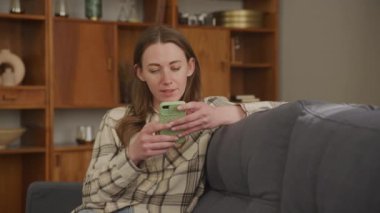 Genç Güzel Kadın, Ev Bekleme Kanepesinde Oturur Akıllı Telefon Oku Süper Haberler Heyecan Duyuyor Başarı, Kazanan ve Piyango Zaferi, Satış ve İndirim, Özel Teklif Alma Konsepti