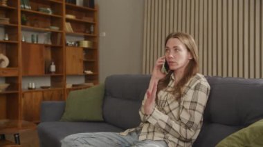 Yakın plan Kadın Evde Arkadaşça Konuşuyor, Pretty Woman 'ın Portresi Modern Koltukta Telefonda Flört Ediyor, Gülümseyen Kız Oturma Odasında Yavaş Çekimde Konuşuyor, yüksek kalite 4K görüntü