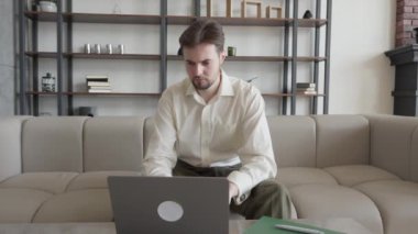 Ofiste Dizüstü bilgisayar kullanan Ciddi Genç İşadamı, Ofiste Çalışan Kafkasyalı Sıradan Adam, Çalışmayı Düşünen, Yüksek Kaliteli 4K görüntü