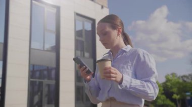 Genç İş Kadınları Konuşuyor İş Merkezi 'nde Akıllı Telefon Kullanıyor Yürüme ve İçme Kahvesi, yüksek kaliteli 4K görüntüler