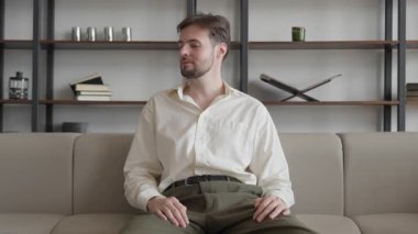 Başarılı adam ofiste koltukta oturuyor ve kameraya gülümsüyor, yüksek kalite 4K görüntü.