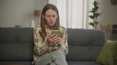 Smartphone 'da Beklenmedik Haberleri okuyan Şaşırmış Kadın Şoka Karşı Tepki Veriyor. Duygusal Tepki, Dijital İletişim, Son Dakika Haberleri, Sosyal Medya Güncellemesi, İnternet Taraması, Endişeli İfade