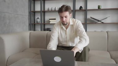 Laptop 'ta çalışan genç adam, modern ofiste konsantre ve ciddi. Odaklanmış Profesyonel, İş Stratejisi, Üretkenlik, Şirket Yaşam Tarzı, Dijital İşyeri, Yüksek Kaliteli 4K Görüntü